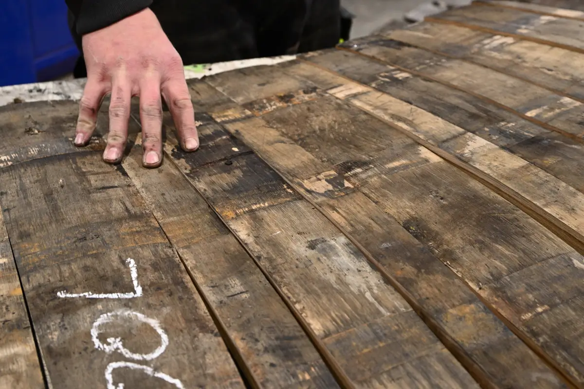 Alte Fassdauben die zum Bau kleiner Fässer - Rückbauten - angereit auf einem tisch liegen mit der Hand eines Küfers drauf.